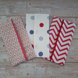 May include: Three folded fabric items with different patterns. One has a repeating diamond pattern with red and white floral accents, another has large blue and red polka dots on a white background, and the third has a red and white chevron pattern.