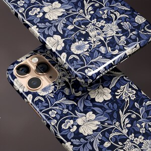 May include: Two phone cases with a glossy finish, featuring a floral pattern in navy blue, light blue, and white. The cases have a detailed design of flowers and leaves. The text "GLOSSY FINISH" is visible on the left side of the image.