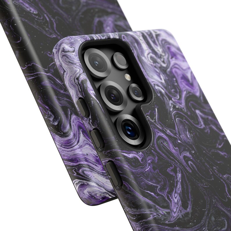 May include: Close-up of two phone cases with a swirling marble design in shades of purple and black. The cases have a glossy finish and feature camera cutouts and side buttons. The overall aesthetic is modern and stylish.