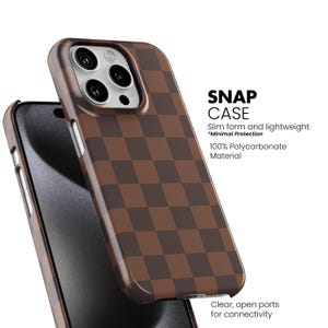 May include: A brown and dark brown checkered Snap Case for a smartphone. The case is made of 100% polycarbonate material and has clear, open ports for connectivity. The text on the case reads "SNAP CASE" and "Slim form and lightweight *Minimal Protection".