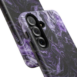 May include: Close-up of two phone cases with a swirling purple and black marble design. The cases have a glossy finish and feature a camera module with three lenses and a flash.