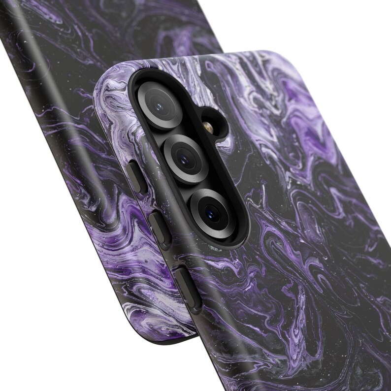 May include: Close-up of two phone cases with a swirling purple and black marble design. The cases have a glossy finish and feature a camera module with three lenses and a flash.