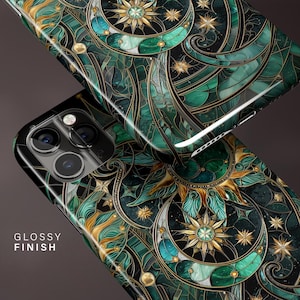 May include: Two glossy phone cases with a detailed stained-glass design. The cases feature a celestial pattern in shades of green, gold, and black, with a sun, moon, and star motif. The text "GLOSSY FINISH" is visible on one case.