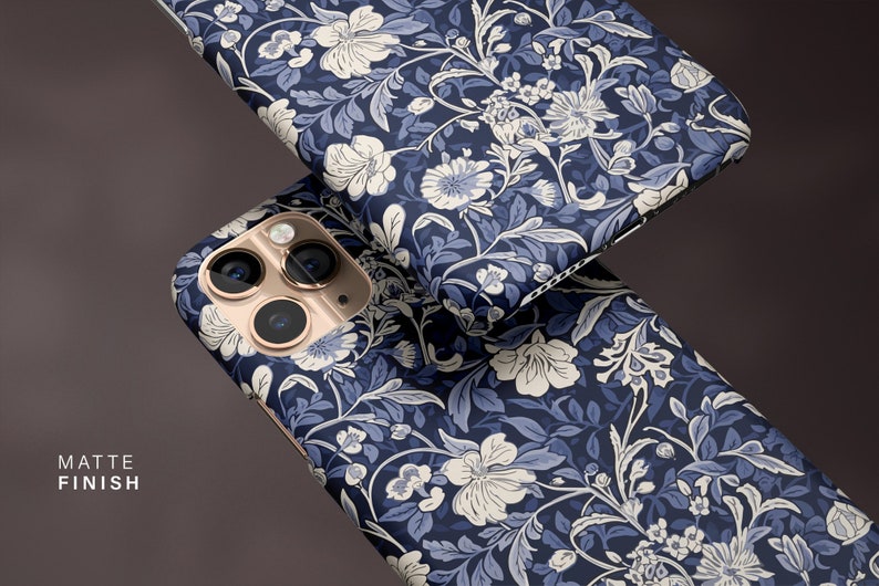 May include: Two phone cases with a floral pattern in navy blue, light blue, and white. The cases have a matte finish. The phone case has a gold camera lens.