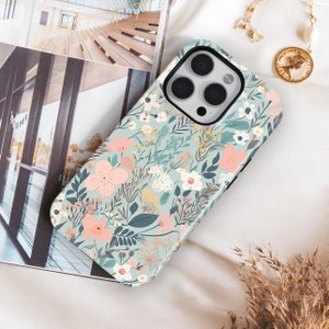 May include: A floral phone case featuring a pastel color palette. The case has a light blue background with a pattern of pink, white, and yellow flowers, along with green leaves. The phone case is lying on a white surface.