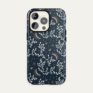 May include: A dark blue phone case with a white floral pattern and gold crescent moons.