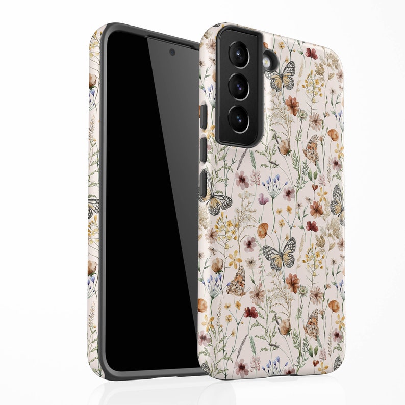 May include: A white phone case with a floral pattern featuring butterflies and wildflowers in shades of brown, yellow, and pink.