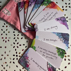 Könnte beinhalten: Satz Affirmationskarten mit Aquarellhintergründen und Mandala-Designs. Die Karten zeigen positive Affirmationen wie "Heute werde ich mir Zeit nehmen, um mich selbst zu verwöhnen", "Ich bin stark", "Ich bin genug", "Ich sehe jede Herausforderung als eine Chance zum Wachstum" und "Ich gebe mein Bestes".