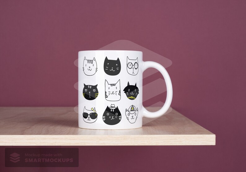 May include: White ceramic mug featuring a repeating pattern of whimsical cat faces in black and white. Each cat has a unique expression and accessory, creating a playful and artistic design. The mug sits on a wooden shelf.