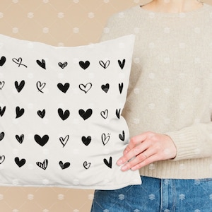May include: White cushion with a black and white pattern of various heart shapes.