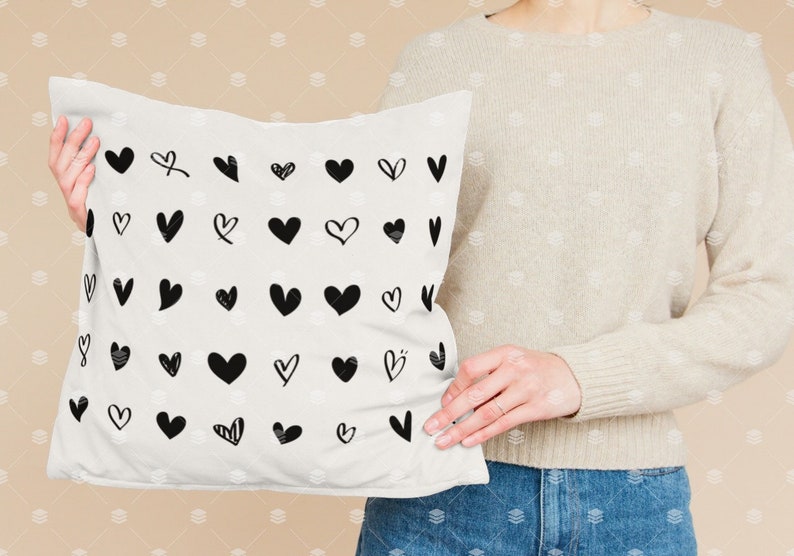 May include: White cushion with a black and white pattern of various heart shapes.