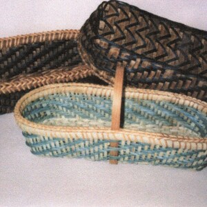 May include: Three oval-shaped woven baskets of varying sizes. One basket features a light blue and natural tan weave, while the other two are constructed from dark brown and black woven material, displaying intricate zigzag patterns throughout.