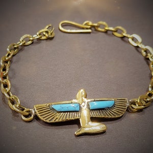 May include: A gold chain bracelet featuring a winged figure pendant. The figure has turquoise blue accents.