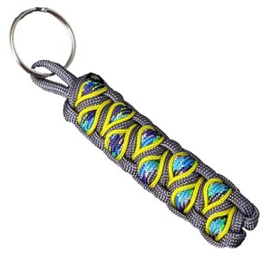 A keychain with a braided design in shades of gray and yellow, featuring a circular metal ring attached to it.