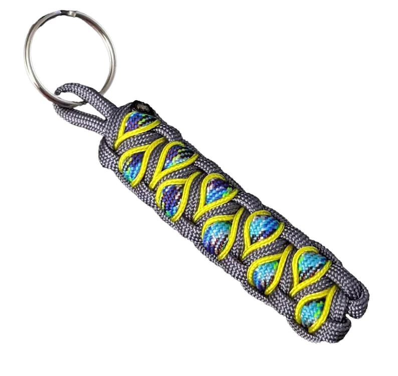 A keychain with a braided design in shades of gray and yellow, featuring a circular metal ring attached to it.