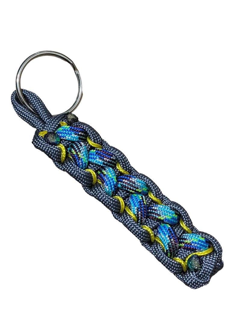 A keychain made of blue and yellow braided cord, with a metal ring attached.