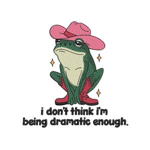 May include: Embroidered design of a green frog wearing a pink cowboy hat and red cowboy boots. The frog has a serious expression and is surrounded by sparkling stars. Text at the bottom reads, "i don't think i'm being dramatic enough."