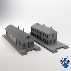 May include: Two grey 3D printed model buildings. The building on the left is a long, rectangular structure with a flat roof and a series of windows along the side. The building on the right is a two-storey structure with a pitched roof and a row of windows on each floor.