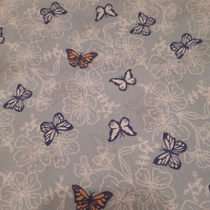 May include: A light blue fabric with a white floral pattern and orange and blue butterflies.