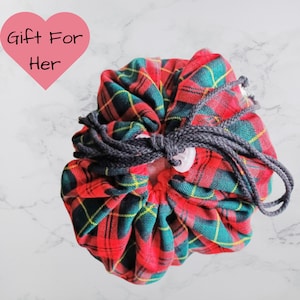 May include: A red, green, and yellow tartan drawstring bag with a grey drawstring closure. The bag is tied with a grey cord and a white button. The words "Gift For Her" are in a pink heart.