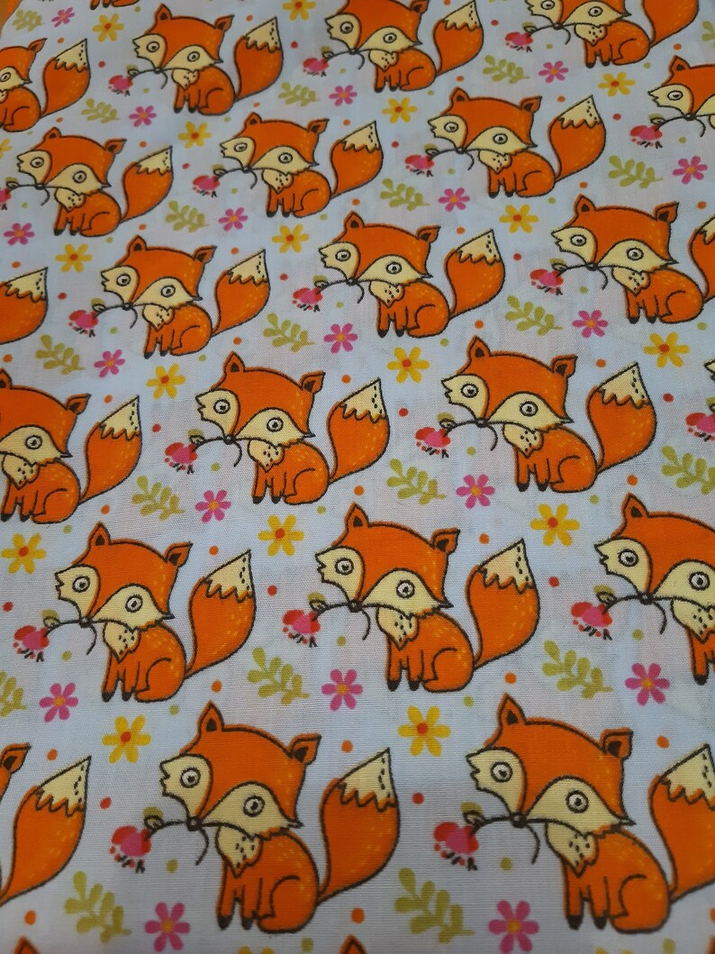 May include: A white fabric with a repeating pattern of orange foxes holding a flower. The foxes have black eyes and a black nose. The flowers are pink, yellow, and green.