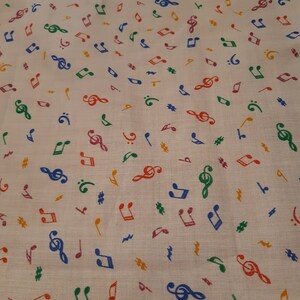 May include: White fabric with a repeating pattern of colourful musical notes. The notes include treble clefs, quavers, crotchets, and sharps.