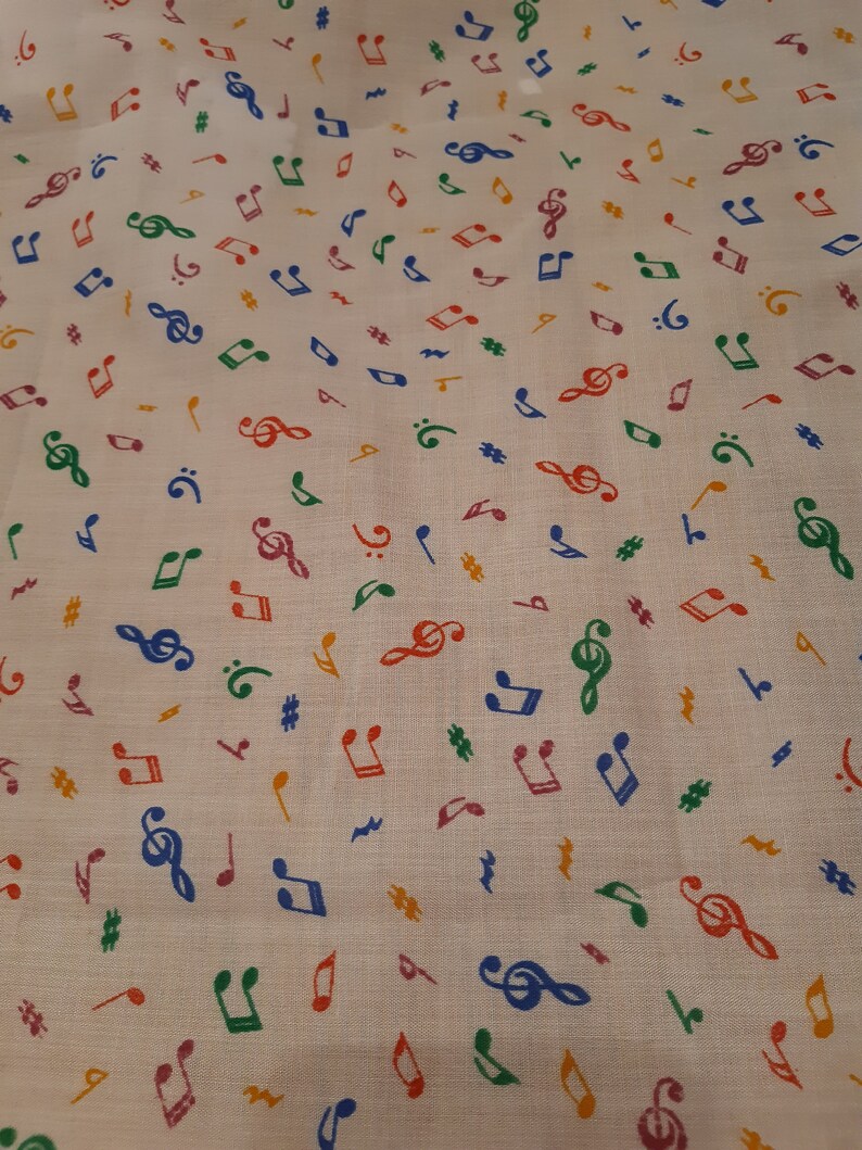 May include: White fabric with a repeating pattern of colourful musical notes. The notes include treble clefs, quavers, crotchets, and sharps.