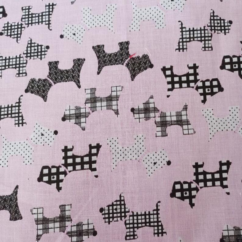 May include: Pink fabric with a repeating pattern of black and white Scottish terrier dogs. Some dogs have a plaid pattern, while others have a polka dot pattern.
