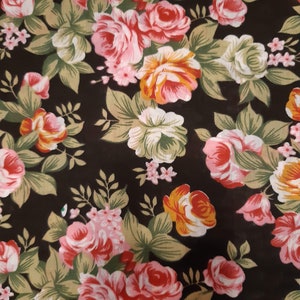 May include: A black fabric with a floral pattern featuring pink, red, and yellow roses. The roses are surrounded by green leaves.