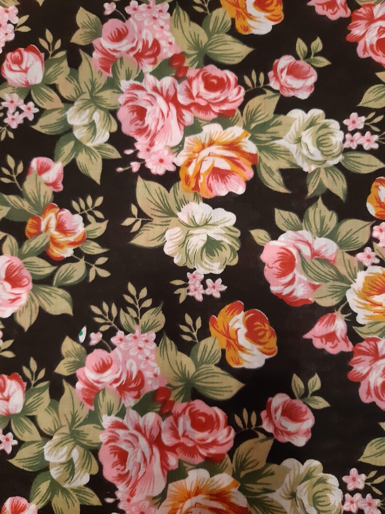 May include: A black fabric with a floral pattern featuring pink, red, and yellow roses. The roses are surrounded by green leaves.