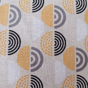 May include: White fabric with a repeating pattern of yellow, grey, and black semi-circles. The semi-circles are made up of concentric circles and dots.