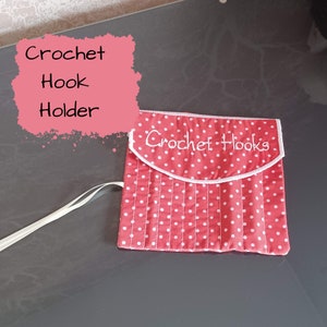 May include: A red and white polka dot crochet hook holder with the words "Crochet Hooks" embroidered on the flap. The holder has a white trim and a white elastic closure.