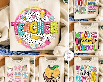 May include: Set of six cream-colored sweatshirts with different back-to-school designs. The designs include "Teacher" with colorful polka dots, "You Are" with a list of positive words, "Welcome Back to School" with a pencil, "Happy First Day of School" with a pencil and apple, a school bus with bows and other school supplies, and an apple with a bow and leopard print.
