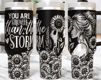 May include: Black stainless steel tumbler with a white design of a woman with sunflowers and the text "You are stronger than the storm".