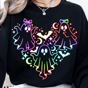 May include: Black sweatshirt with a rainbow-colored design of three ghosts with bows on their heads. The ghosts are arranged in a heart shape with bats and stars around them.