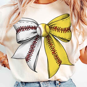 Op de afbeelding: Crèmekleurig T-shirt met een softbal-thema strikdesign. De strik bestaat uit een wit en geel lint, met een softbal in het midden. Het ontwerp bevat rode stikseldetails, waardoor een sportieve en opvallende afbeelding ontstaat.