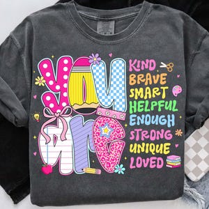 May include: Dark gray sweatshirt with the words "YOU ARE" in colorful, playful lettering. The design includes the words "KIND, BRAVE, SMART, HELPFUL, ENOUGH, STRONG, UNIQUE, LOVED" in a variety of fonts and colors. The sweatshirt has a vintage wash.