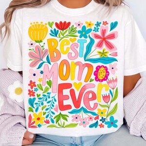 May include: White t-shirt with a colorful floral design and the text "Best Mom Ever" in a rainbow gradient.