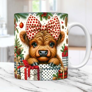 May include: White ceramic mug with a Christmas-themed design featuring a Highland cow with a red and white polka dot bow, peeking out of a box with red and white polka dot wrapping paper. The mug has a white handle.