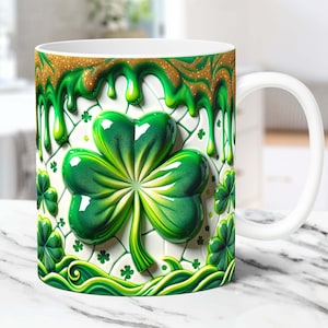 May include: White ceramic mug with a green shamrock design. The shamrock is 3D and has a shiny, glossy finish. Green and gold dripping paint surrounds the shamrock.