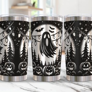 Może przedstawiać: Trzy czarno-białe kubki ze stali nierdzewnej z przerażającym wzorem na Halloween. Wz&oacute;r przedstawia ducha, dynie i girlandy świetlne.