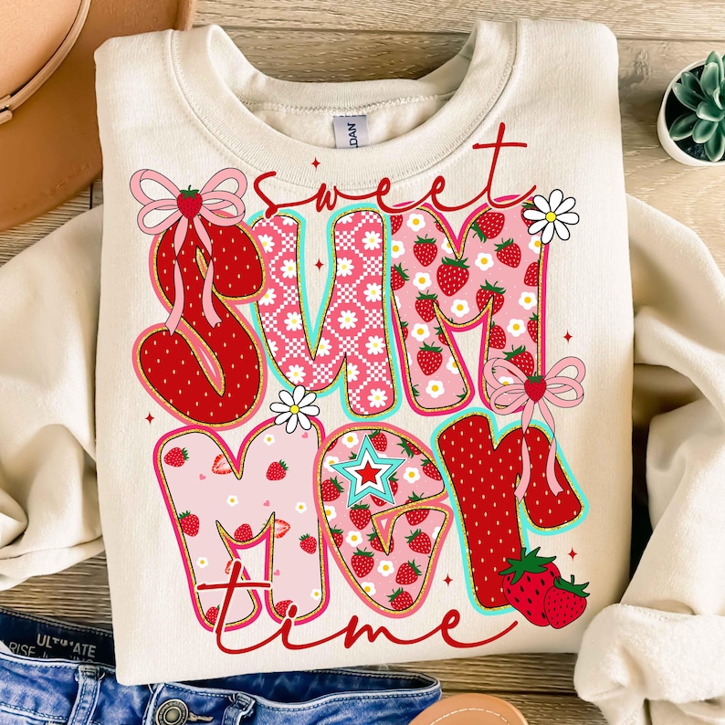 Pu&ograve; includere: Una felpa color crema con un design a patchwork delle parole "sweet summer time" in rosso, rosa e bianco. Le lettere sono decorate con fragole, fiori e fiocchi.