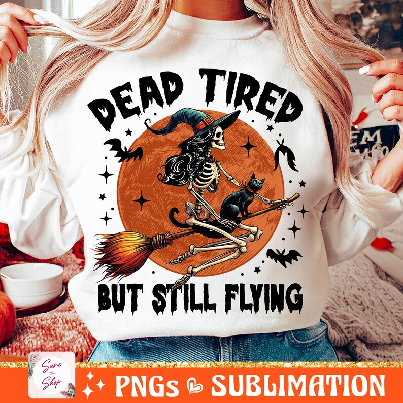 May include: White sweatshirt with a graphic of a skeleton witch riding a broomstick with a black cat. The text "Dead Tired But Still Flying" is printed on the shirt.