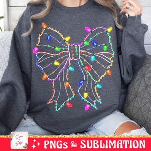May include: A gray sweatshirt with a white outline of a bow made of Christmas lights. The lights are multi-colored and include red, green, blue, yellow, orange, and purple.