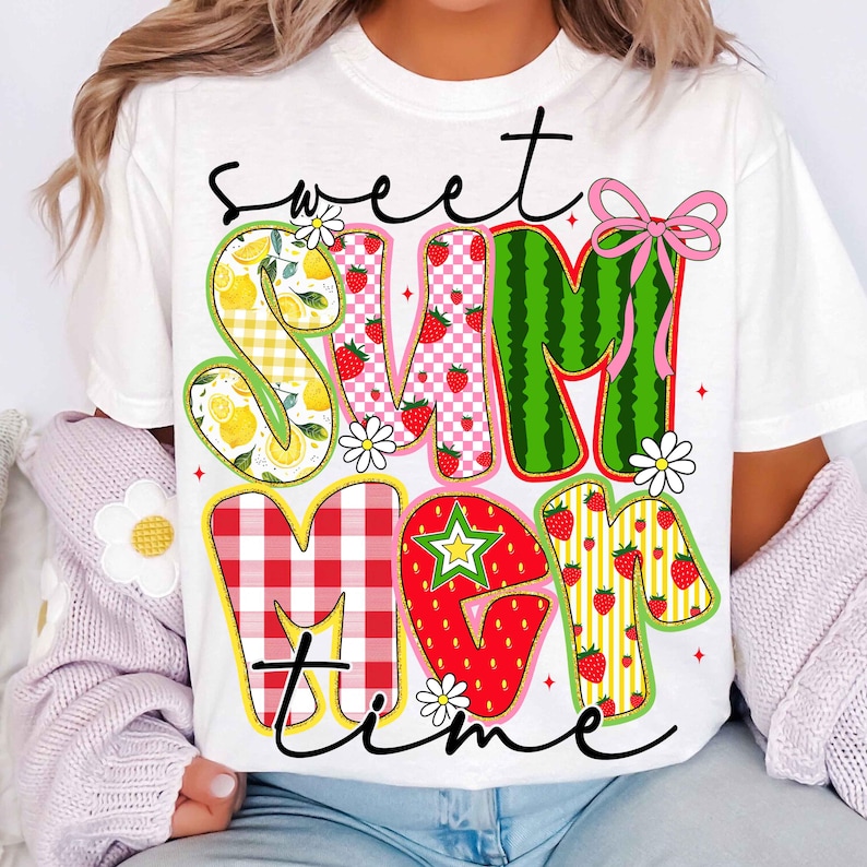 以下が含まれることがあります： カラフルな「Sweet Summer Time」グラフィックがプリントされた白いTシャツ。レモン、イチゴ、スイカ、ギンガムチェック柄で埋められた文字のデザインで、デイジーとピンクのリボンがアクセントになっています。