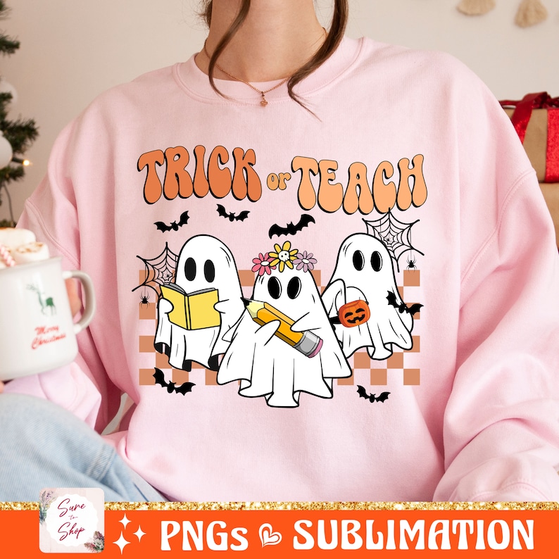 May include: Pink sweatshirt featuring a design of three ghosts. The ghosts are holding a book, a pencil, and a pumpkin. The text "Trick or Teach" is above the ghosts in a retro font.