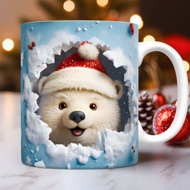 Peut inclure: Une tasse en c&eacute;ramique blanche avec une sc&egrave;ne d'hiver bleue et blanche. Un ours polaire portant un bonnet de P&egrave;re No&euml;l rouge sort d'un trou dans la neige.
