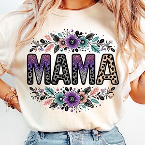May include: A white t-shirt featuring a floral design and the word "MAMA" in black with a leopard print pattern.