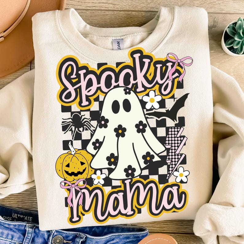 Puede incluir: Sudadera color crema con un gr&aacute;fico tem&aacute;tico de Halloween. El dise&ntilde;o presenta un fantasma, una calabaza, una ara&ntilde;a, un murci&eacute;lago y las palabras "Spooky Mama" en una fuente l&uacute;dica. El fondo incluye un patr&oacute;n de cuadros y detalles florales.