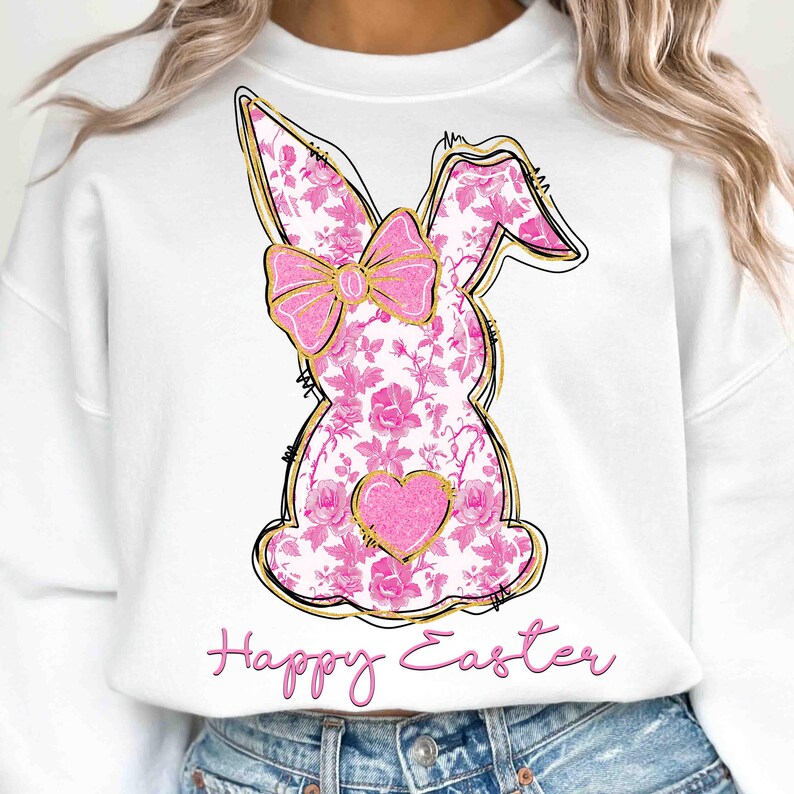 Op de afbeelding: Wit sweatshirt met een roze bloemenkonijn met een gouden strik en een roze hart. De tekst "Happy Easter" is onder het konijn gedrukt.